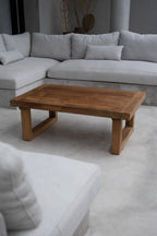 Table basse en teck récupéré dans un séjour, devant un canapé d'angle gris