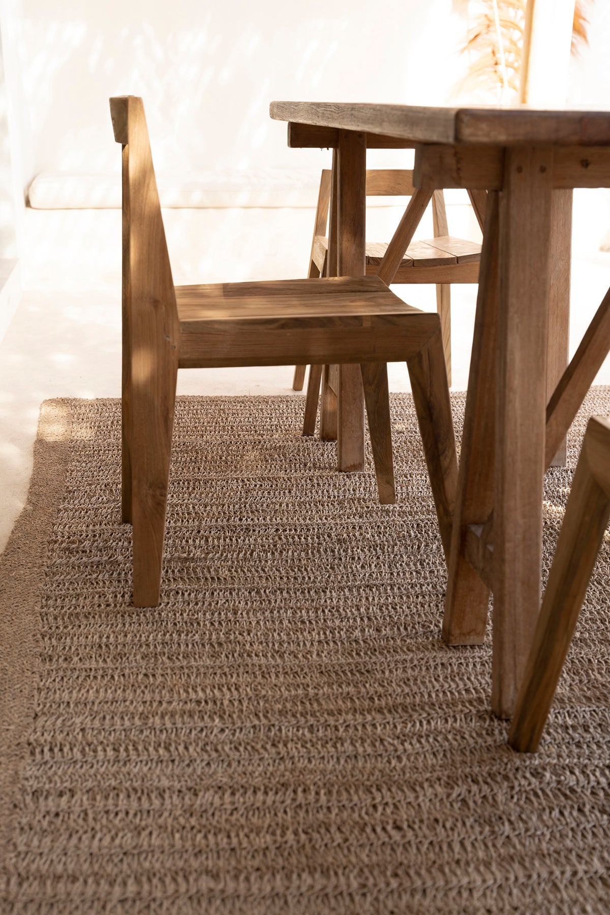 Chaises Paxi en teck autour d'une table en bois, sur un tapis