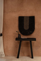 Décoration murale Dada noire accrochée au-dessus d'une console, sur un mur terracotta