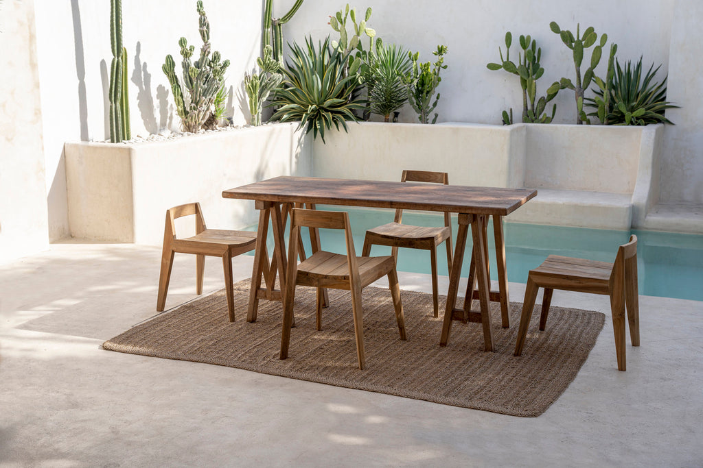 Plusieurs chaises Paxi en teck autour d'une table de terrasse, sur un tapis en fibre naturelle
