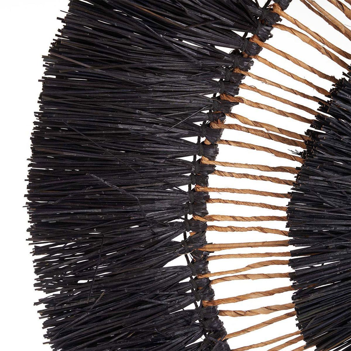 Gros plan sur les fibres naturelles noires et beiges de la décoration murale Maurea