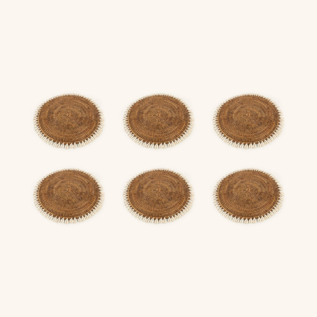 Visualisation du lot de 6 sets de table en rotin et cauris, composée à partir du visuel du produit unitaire ; le nombre et la taille des cauris varient sur chaque set.