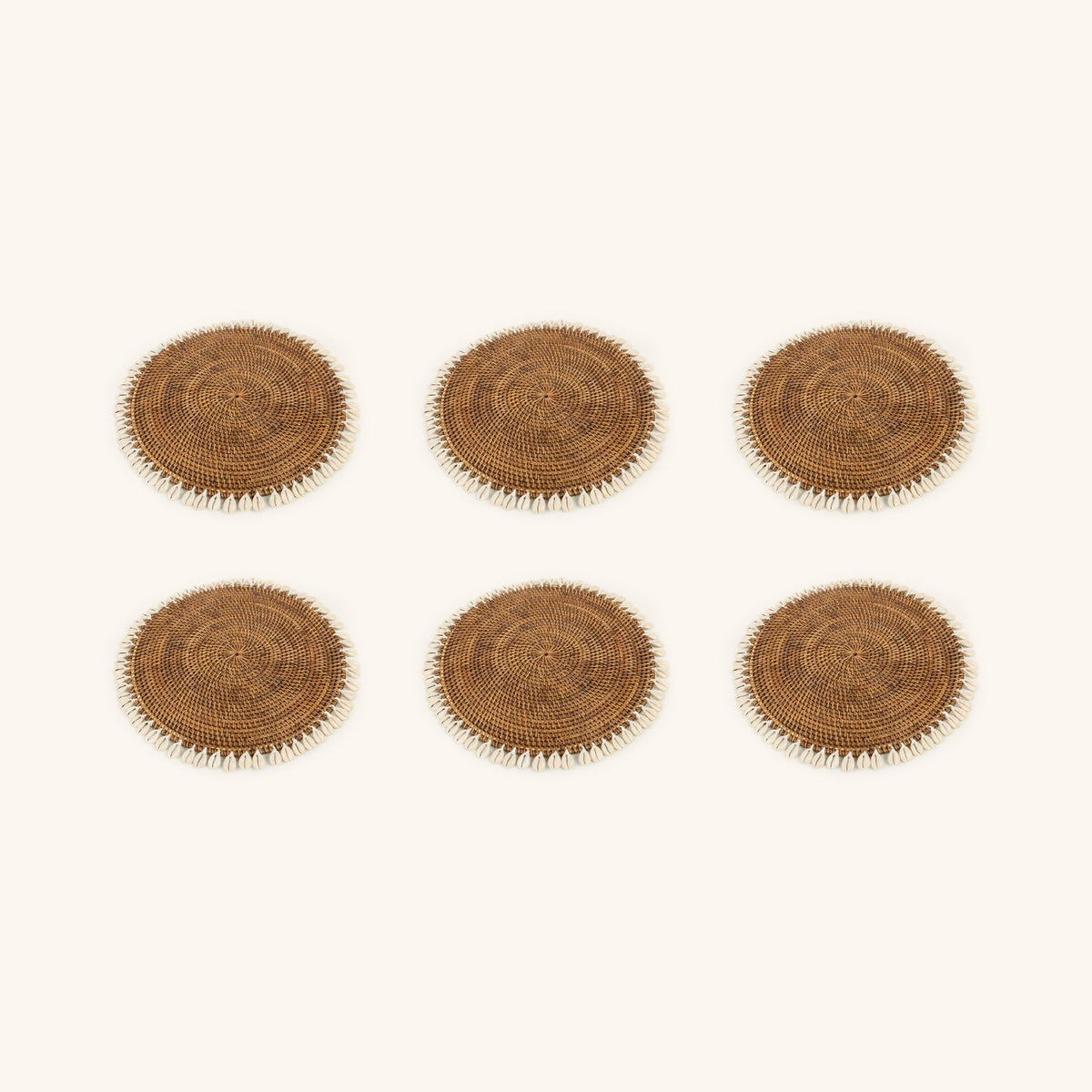 Visualisation du lot de 6 sets de table en rotin et cauris, composée à partir du visuel du produit unitaire ; le nombre et la taille des cauris varient sur chaque set.