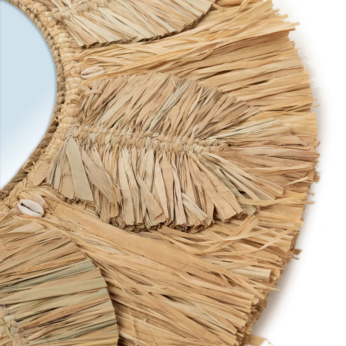 Gros plan sur les feuilles de raphia et les petits coquillages cauris du miroir Palmier