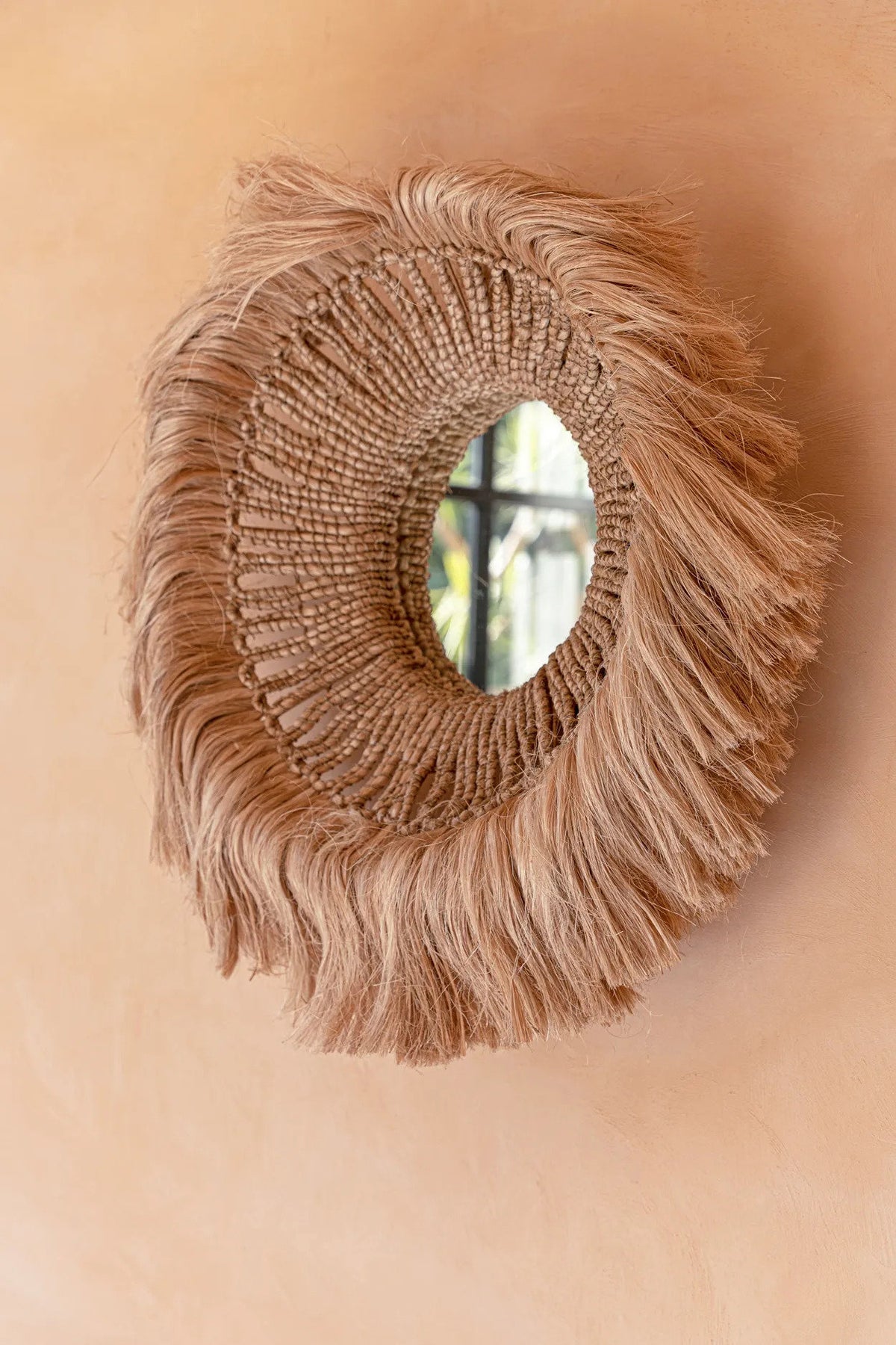Miroir Salomon accroché sur un mur terracotta, vue rapprochée