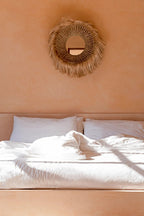 Miroir Salomon accroché au-dessus d'un lit dans une chambre aux murs terracotta