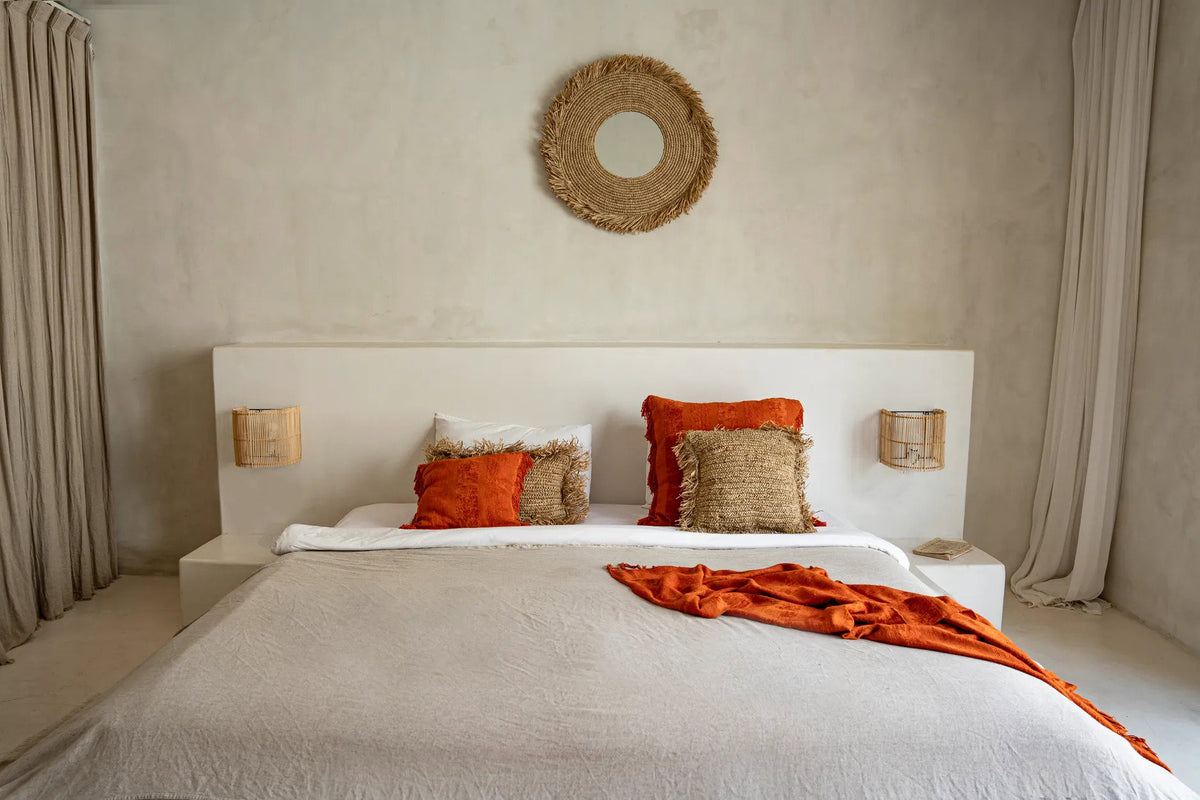Miroir Yema accroché au-dessus d'une tête de lit dans une chambre claire