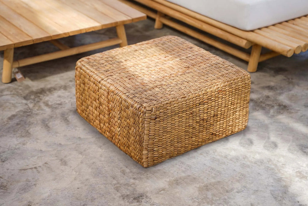 Pouf carré en jacinthe d'eau devant une banquette basse en teck