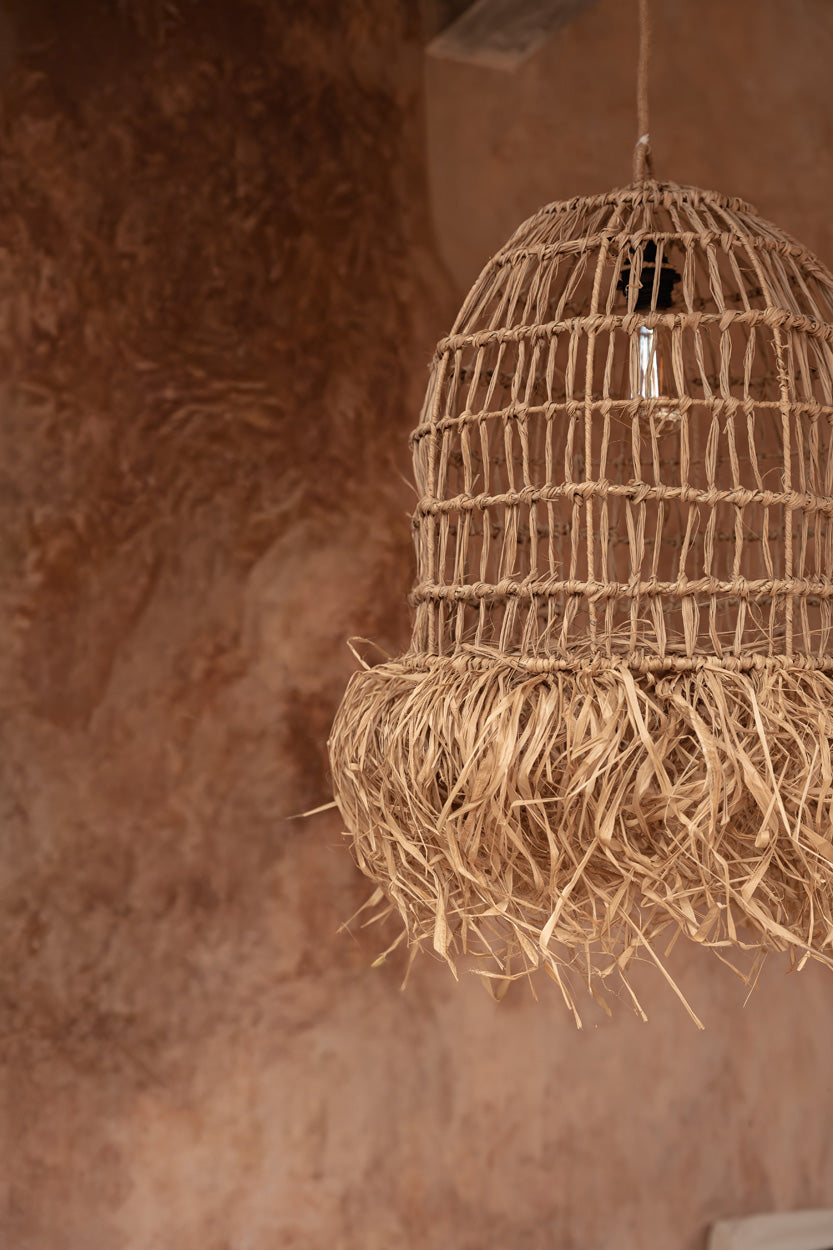 Abat-jour Casita suspendu devant un mur terracotta dans un intérieur chaleureux