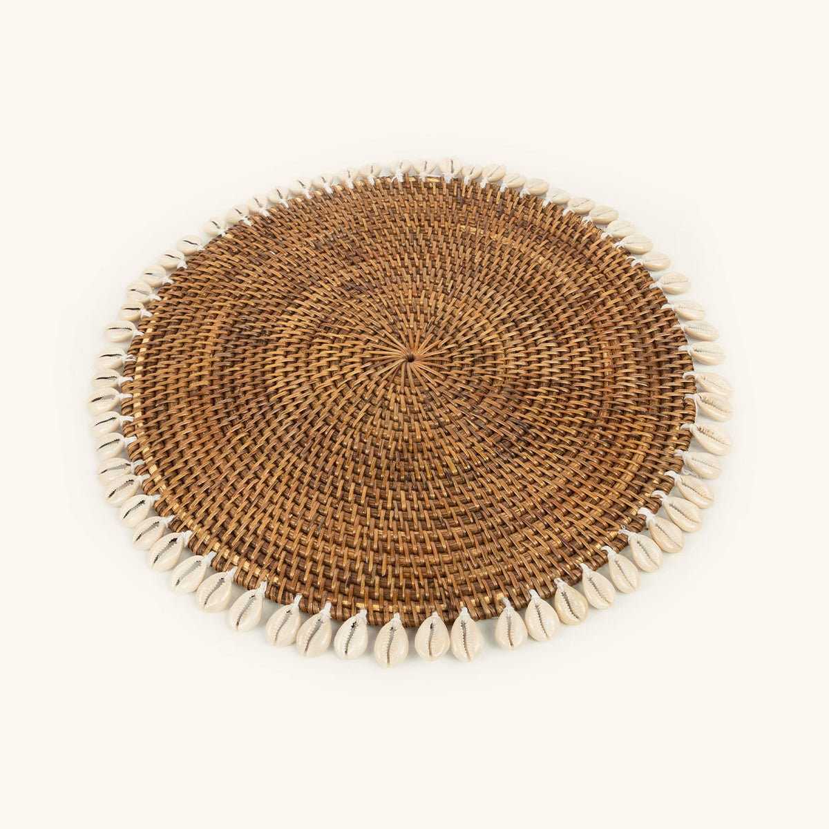 Set de table rond en rotin tressé bordé de coquillages cauris, vu de dessus